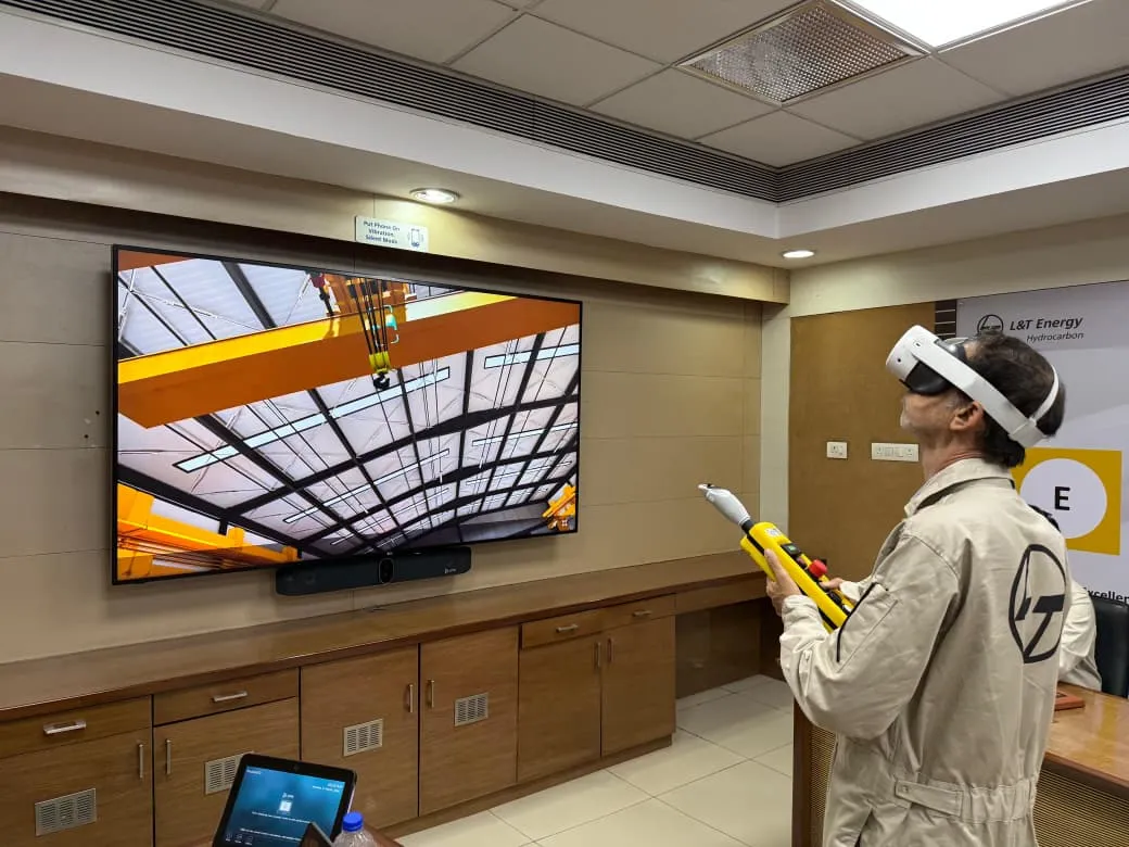 Operator using a VR headset and pendant controller to practise overhead crane operation on the Arise Crane Simulator at L&T Energy
