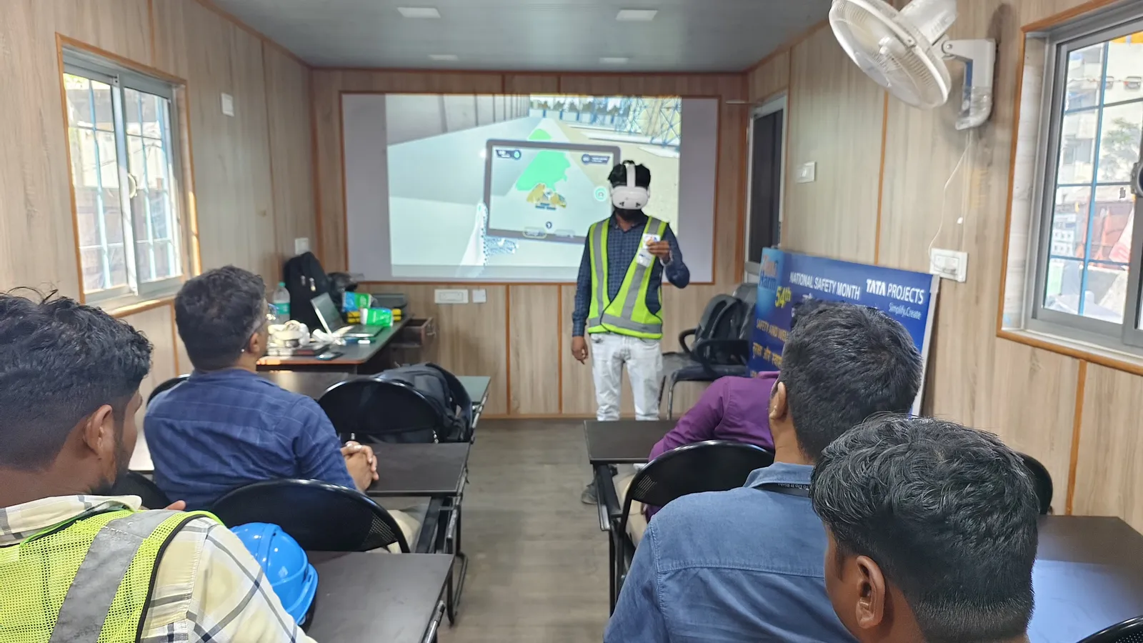 Presenter running a Safetizen VR safety training session for a seated audience during National Safety Month at a TATA Projects site office